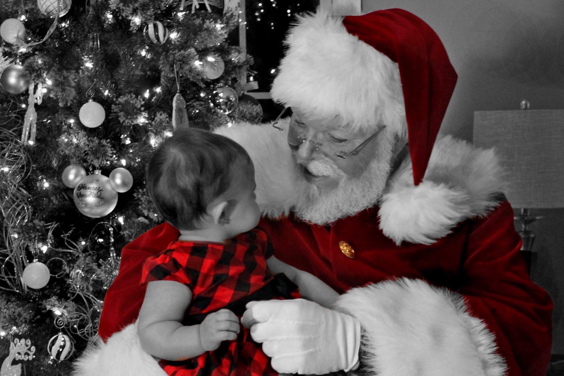 Santa CJ Kringle kneeling beside a smiling child